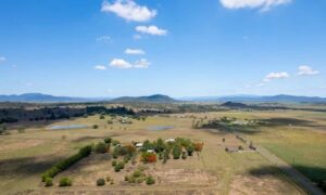 Aerial view of a rural homesite with open fields, access roads, and nearby ponds, illustrating site conditions to consider when planning a perc test