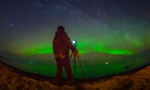 Surveyor using GPS equipment under aurora lights during a solar storm, showing how space weather can affect an ALTA land title survey