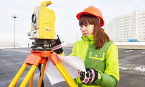 Surveyor using a total station while reviewing field notes for an ALTA title survey on a commercial site