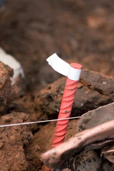 Boundary pin marker in soil highlighting field challenges of an ALTA title survey
