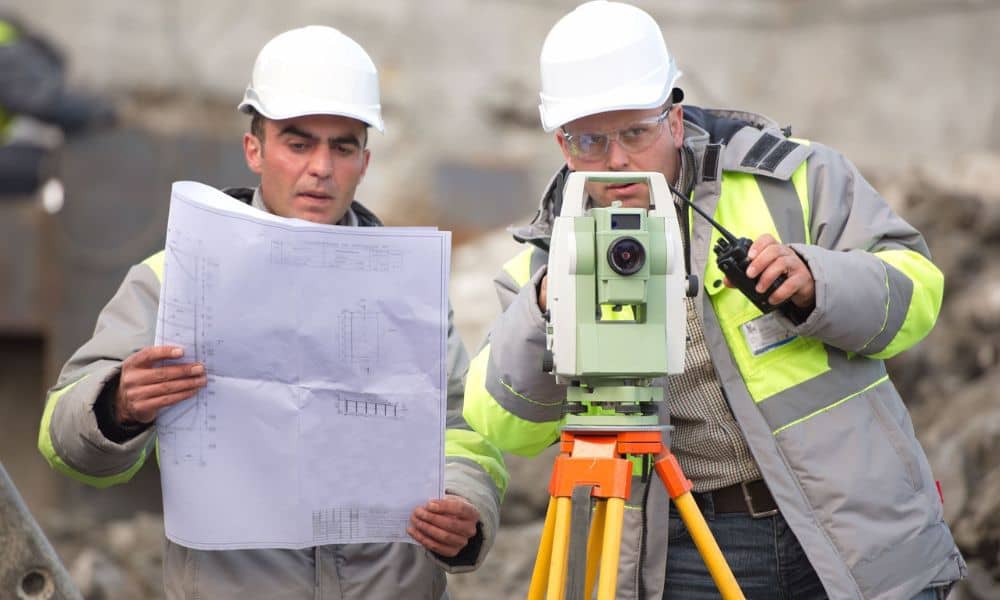 Surveyors reviewing plans and using total station equipment while collecting utility records for an ALTA land title survey
