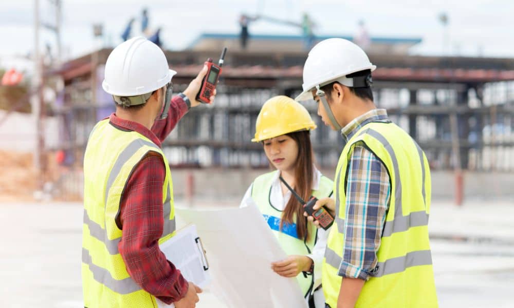 Survey team wearing hard hats and safety vests reviewing plans at a commercial site during an ALTA title survey