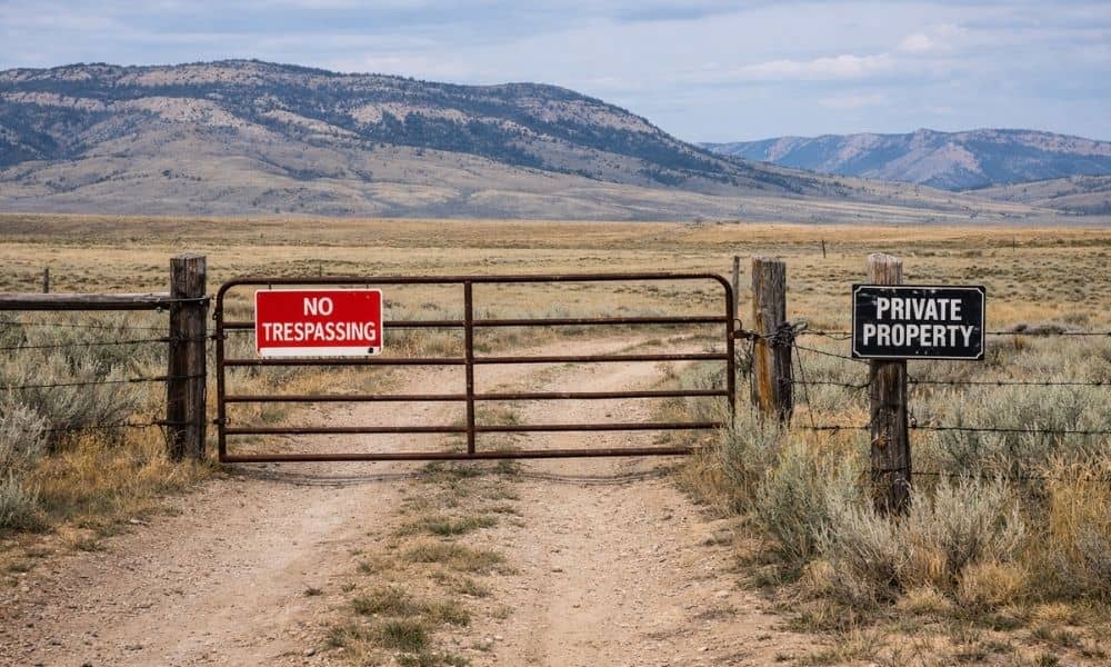 Dirt road leading to open rural land with a fence showing limited access, highlighting how an alta land survey helps identify property access issues