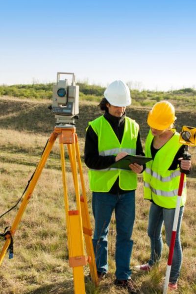 Surveyors using a total station during an alta land title survey to verify property boundaries and easement locations on site