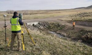 A survey crew completes a topographic survey near a drainage channel in rural Wyoming